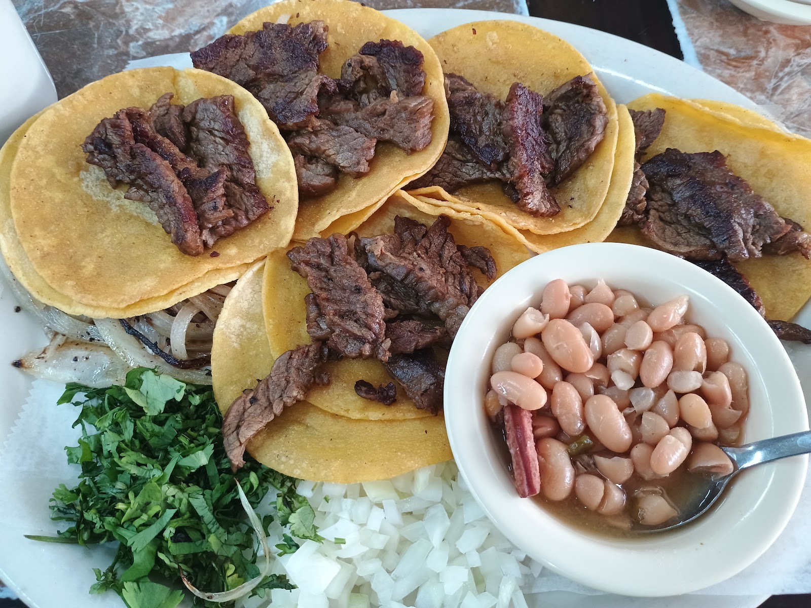 Carne asada street tacos with cilantro, onion and beans